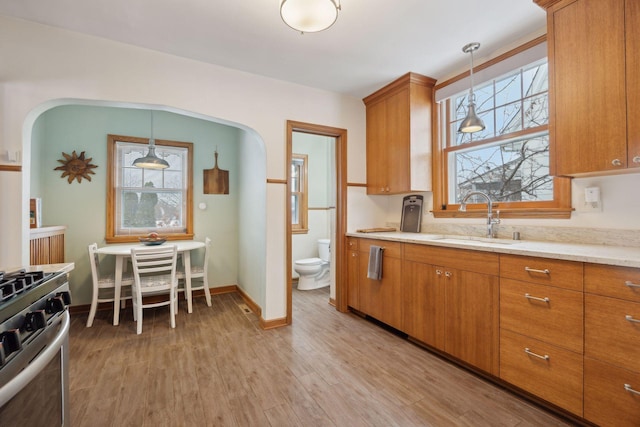 kitchen with sink, decorative light fixtures, light hardwood / wood-style flooring, and stainless steel range oven