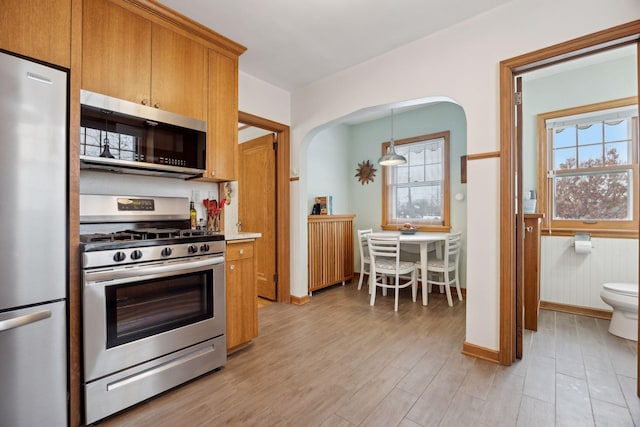 kitchen featuring pendant lighting, appliances with stainless steel finishes, and light wood-type flooring