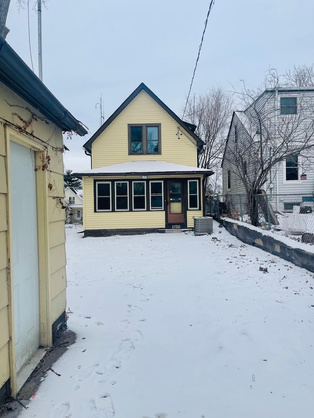 snow covered back of property featuring central AC unit