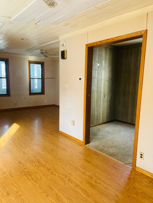 empty room with ceiling fan, plenty of natural light, wooden ceiling, and light wood-type flooring