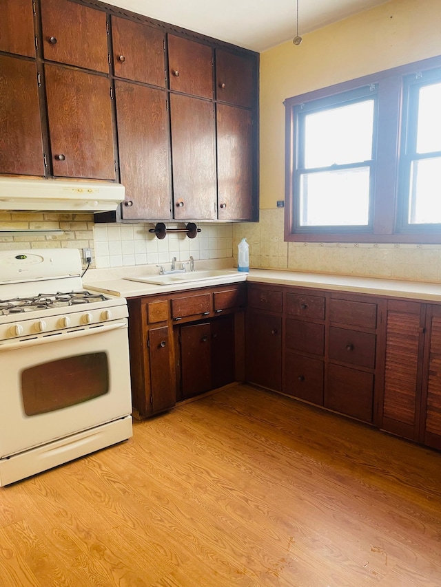 kitchen featuring tasteful backsplash, light hardwood / wood-style floors, and white gas stove