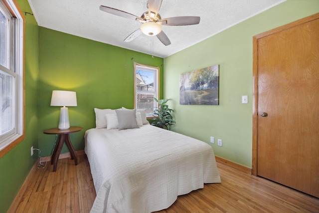 bedroom with a textured ceiling, light wood finished floors, and baseboards