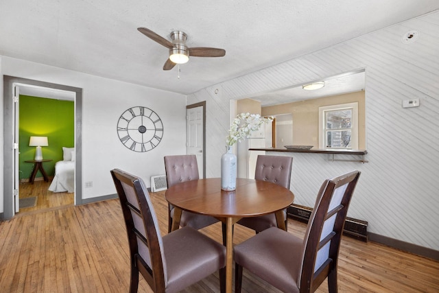 dining space featuring light wood-style flooring, visible vents, baseboards, and ceiling fan