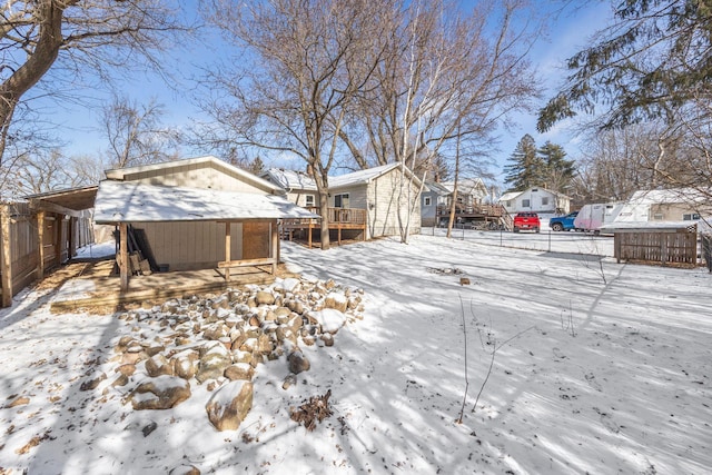 yard covered in snow with a residential view and fence