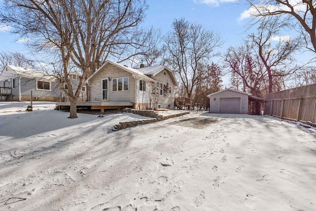 view of front of home with a detached garage, a chimney, fence, driveway, and an outdoor structure