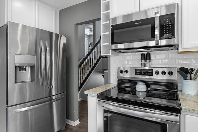 kitchen with dark hardwood / wood-style floors, tasteful backsplash, white cabinetry, stainless steel appliances, and light stone countertops