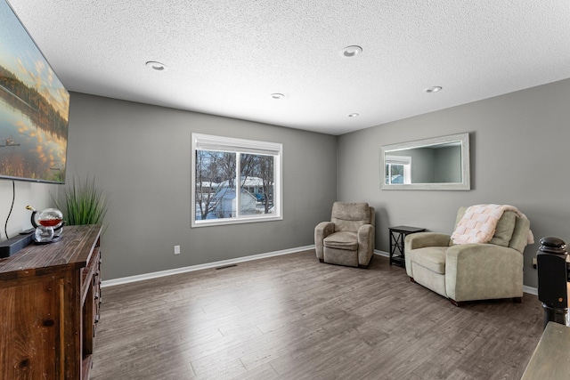 living area with wood-type flooring and a textured ceiling