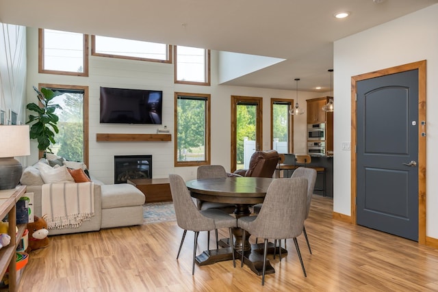 dining space featuring a wealth of natural light, a large fireplace, and light wood-type flooring