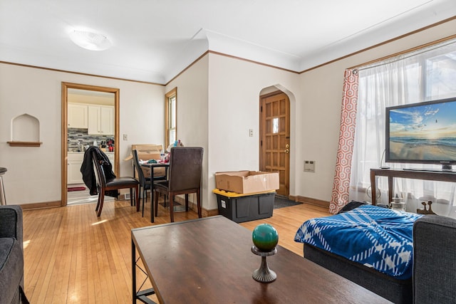 bedroom with arched walkways, light wood finished floors, multiple windows, and baseboards