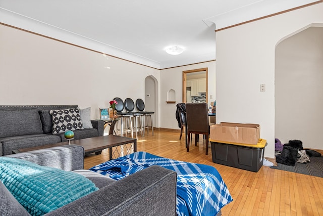 living room with arched walkways, baseboards, hardwood / wood-style flooring, and crown molding