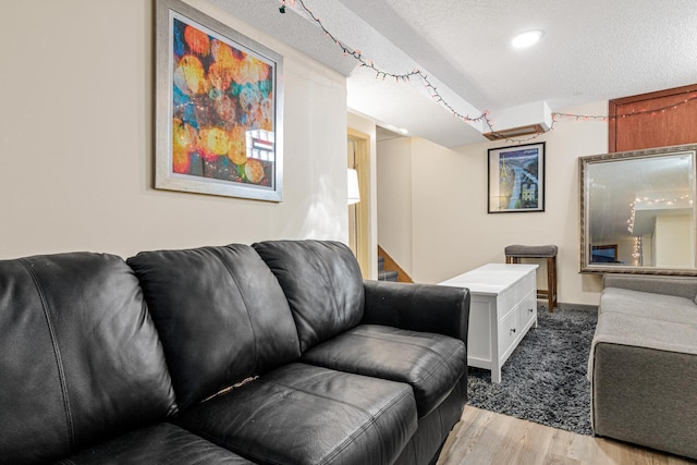 living area featuring a textured ceiling, light wood finished floors, and stairs