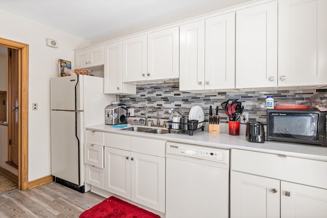 kitchen with light countertops, decorative backsplash, white cabinetry, a sink, and white appliances