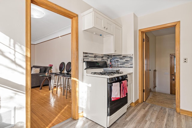 kitchen featuring light wood finished floors, gas range gas stove, visible vents, and white cabinetry