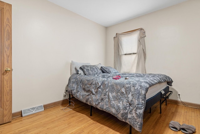 bedroom with baseboards, visible vents, and hardwood / wood-style floors