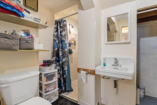 full bath with a shower with curtain, a sink, concrete block wall, and toilet