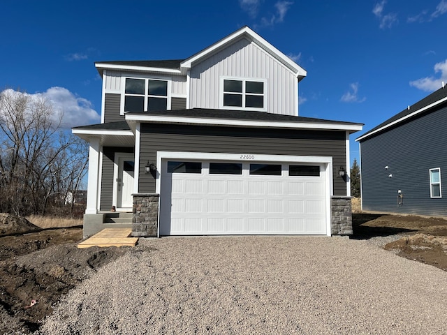 view of front of home with board and batten siding, stone siding, driveway, and a garage