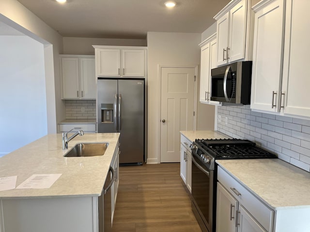 kitchen featuring white cabinets, wood finished floors, a kitchen island with sink, stainless steel appliances, and a sink