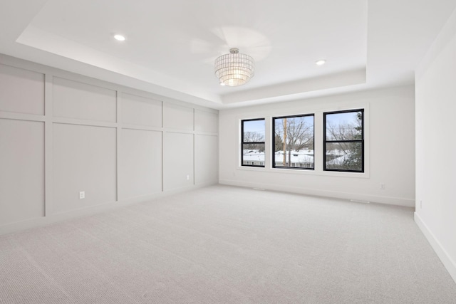 empty room featuring light colored carpet and a tray ceiling