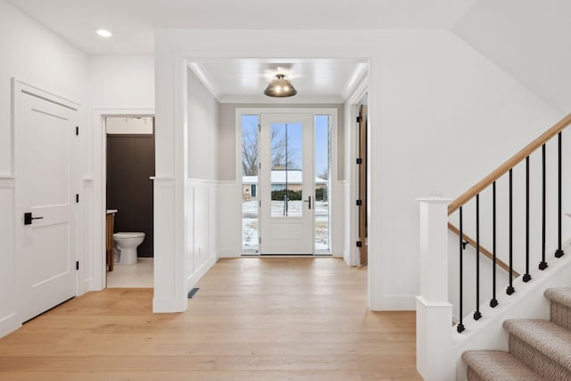 entryway with crown molding and light hardwood / wood-style floors