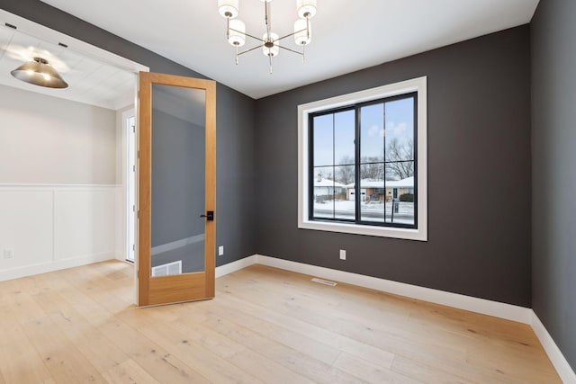 spare room with an inviting chandelier and light wood-type flooring