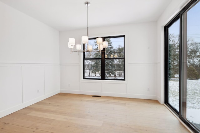 unfurnished dining area featuring a chandelier and light hardwood / wood-style floors