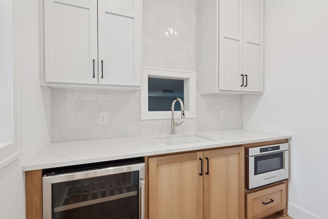 kitchen with white cabinetry, oven, sink, and beverage cooler