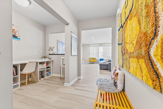 hallway featuring light hardwood / wood-style floors and a textured ceiling