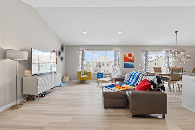 living room featuring a notable chandelier, a healthy amount of sunlight, and light wood-type flooring