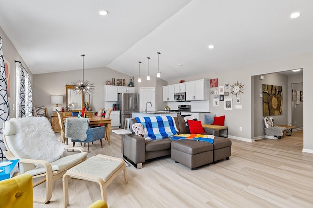 living room featuring vaulted ceiling, sink, an inviting chandelier, and light hardwood / wood-style floors