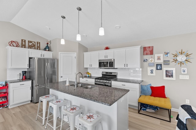 kitchen featuring sink, dark stone countertops, appliances with stainless steel finishes, an island with sink, and white cabinets