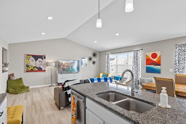 kitchen featuring pendant lighting, white cabinetry, sink, dark stone countertops, and stainless steel dishwasher