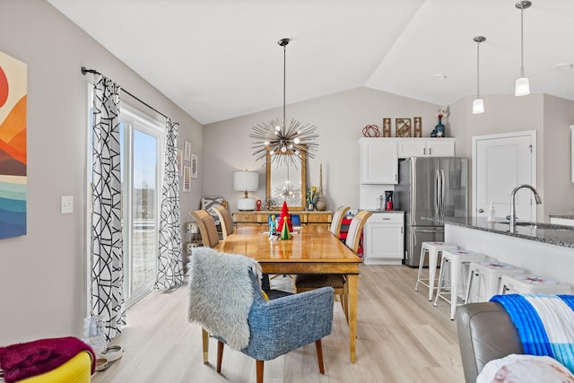 dining space with vaulted ceiling, sink, an inviting chandelier, and light wood-type flooring