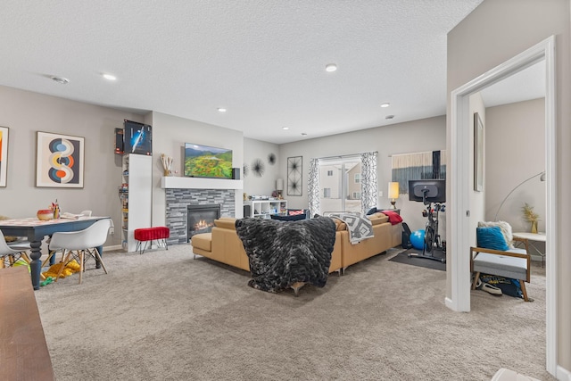 living room featuring a stone fireplace, carpet floors, and a textured ceiling