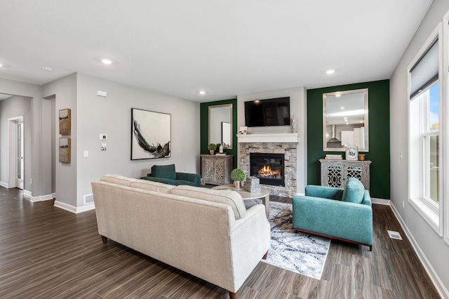 living room featuring a stone fireplace and dark hardwood / wood-style floors