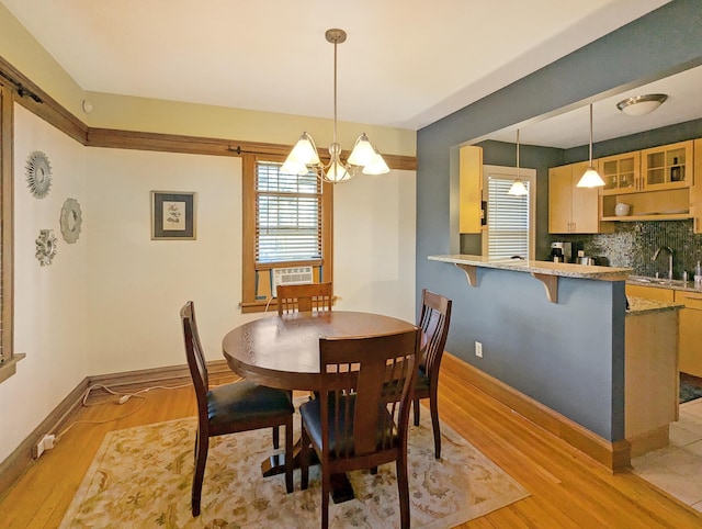 dining room featuring cooling unit, an inviting chandelier, and light hardwood / wood-style flooring