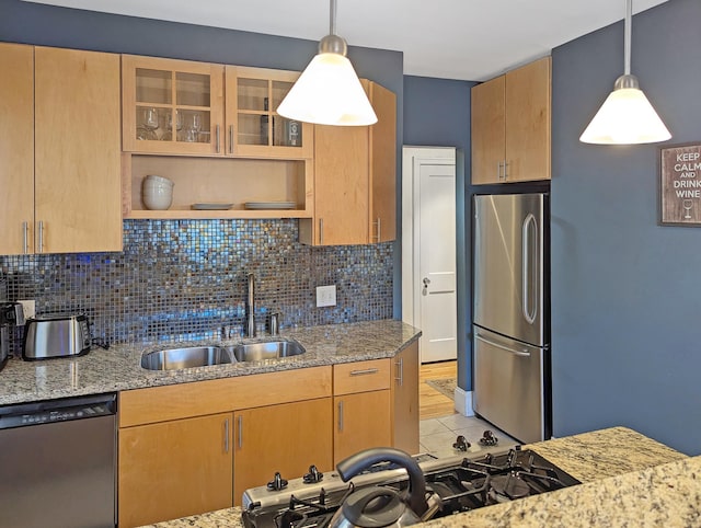 kitchen featuring sink, hanging light fixtures, appliances with stainless steel finishes, light stone countertops, and decorative backsplash