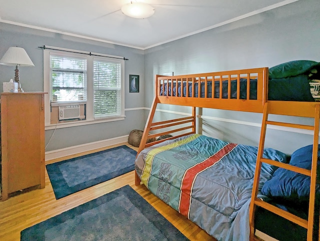 bedroom featuring cooling unit, ornamental molding, and hardwood / wood-style floors