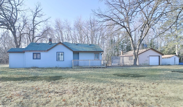 exterior space featuring a chimney, metal roof, an outbuilding, a yard, and a garage