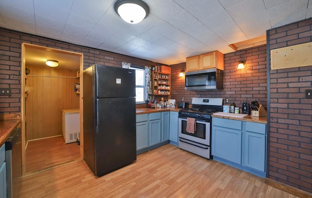 kitchen featuring brick wall, stainless steel appliances, and light wood-style flooring