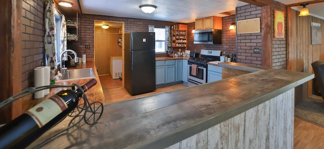 kitchen with stainless steel appliances, open shelves, brick wall, and a sink