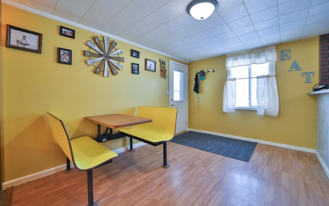dining space with baseboards, wood finished floors, and ornamental molding