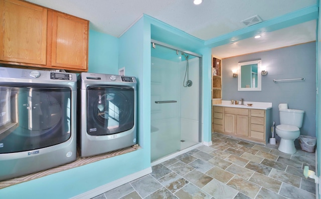 laundry room featuring laundry area, stone finish floor, a sink, visible vents, and washer and clothes dryer