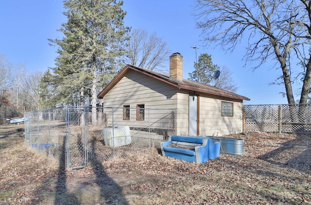 back of house featuring fence, a chimney, and a gate