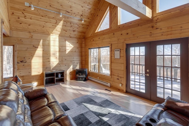 unfurnished living room with a baseboard heating unit, wood walls, high vaulted ceiling, and french doors