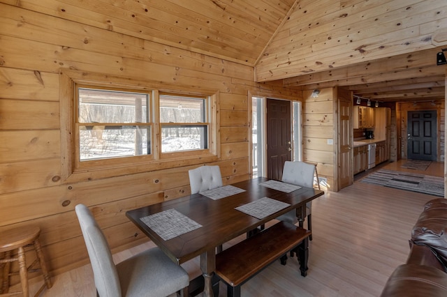 dining area featuring vaulted ceiling, light hardwood / wood-style floors, wooden ceiling, and wood walls