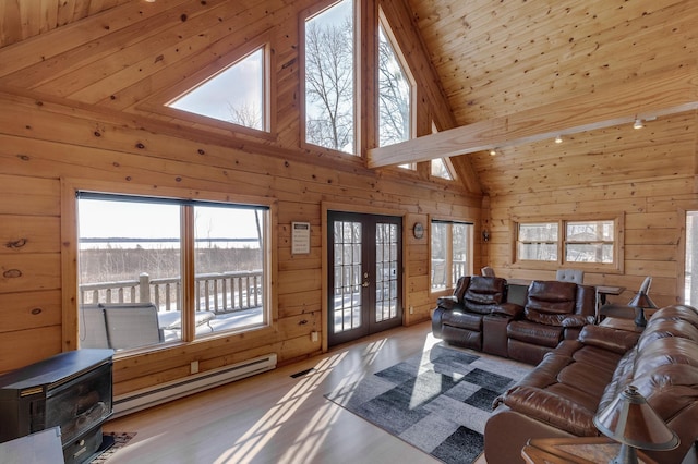 11375 Grouse Loop NW, Walker, MN 56484 - living area featuring a baseboard heating unit, wood walls, high vaulted ceiling, french doors, and a wood stove