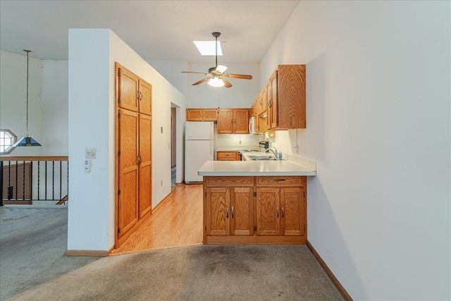 kitchen with sink, a skylight, light carpet, kitchen peninsula, and white fridge