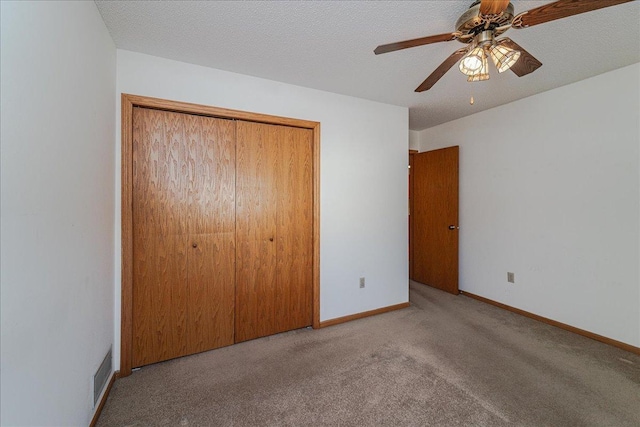 unfurnished bedroom with ceiling fan, light colored carpet, a closet, and a textured ceiling