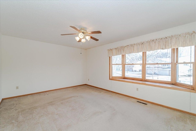 empty room with light carpet, ceiling fan, and a textured ceiling