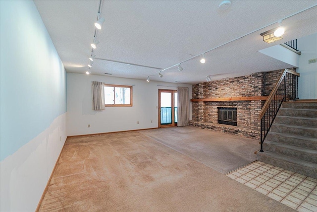 unfurnished living room with track lighting, a brick fireplace, light carpet, and a textured ceiling